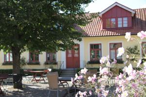 una casa con tavoli, sedie e fiori rosa di Blåsingsborgs Gårdshotell på Österlen a Kivik