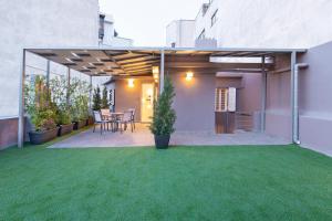 een achtertuin met een patio met groen gras bij Acropolis Stay in Athene