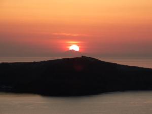 a sunset over a island in the ocean at Yposkafo Suites - Studio - Santorini in Fira