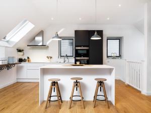 a kitchen with a white island and two bar stools at Taymore Lodge in Kenmore