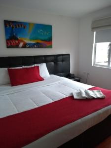 a bedroom with a large white bed with a red pillow at Hotel Feria Nova in Bogotá