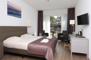ein Hotelzimmer mit einem Bett, einem Schreibtisch und Stühlen in der Unterkunft Hotel Cafe Restaurant Duinzicht in Schiermonnikoog