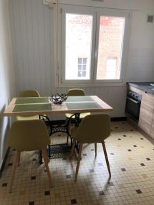 een keuken met een tafel en stoelen en 2 ramen bij Villa Coquelicot Industriel in Le Tréport