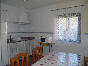 a kitchen with a table with chairs and a microwave at Fuentes de Abajo in San Esteban de la Sierra