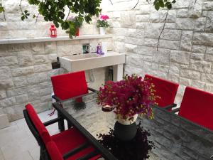 a table with red chairs and a sink and flowers at Apartman Crnica in Šibenik