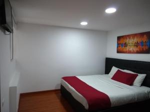 1 dormitorio con 1 cama con manta roja y blanca en Hotel Feria Nova, en Bogotá