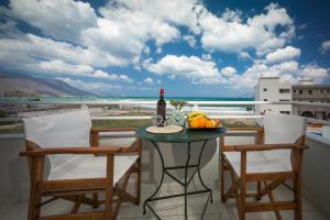 un tavolo con una bottiglia di vino e frutta sul balcone di Sea Daffodil apartments a Kíssamos