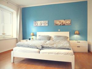 a bedroom with a white bed with a blue wall at Ferienwohnung Strandläufer in Kühlungsborn