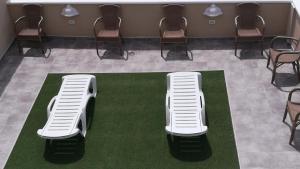 サンミゲル・デ・アボナにあるEmblema Suites 3の待合室の緑の絨毯の上に座る白い椅子2脚