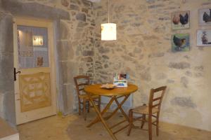 una mesa y sillas en una habitación con una pared de piedra en La Colline Bleue, en Banne