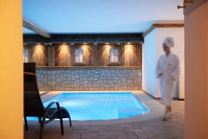 a woman in white standing next to a swimming pool at Chalet Grumer Suites&Spa in Soprabolzano