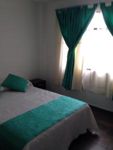 a bedroom with a bed with green curtains and a window at Hotel Casa Medina in San Mateo