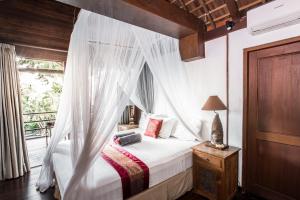 een slaapkamer met een hemelbed en een raam bij Villa Puri Burung in Canggu +53 foto's