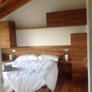 Schlafzimmer mit einem großen Bett mit einem Kopfteil aus Holz in der Unterkunft Rooms dei Minatori in Pergine Valsugana