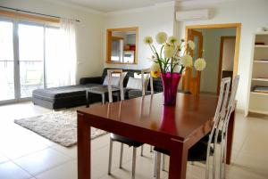 una mesa de comedor con un jarrón de flores. en Casa das Ondas Al-Gharb, en Armação de Pêra