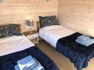 two twin beds in a room with wooden walls at Lunecliffe Country lodge-Lancaster Gateway to the Lakes in Lancaster