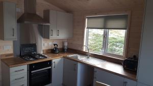 uma cozinha com armários brancos, um lavatório e uma janela em Lunecliffe Country lodge-Lancaster Gateway to the Lakes em Lancaster