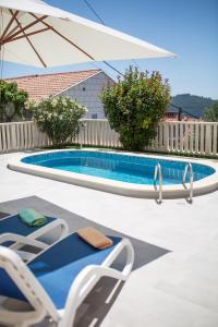 een zwembad met 2 ligstoelen en een parasol bij Villa Juliet in Dubrovnik