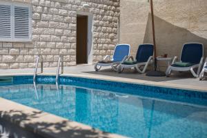 - un groupe de chaises assises à côté de la piscine dans l'établissement Villa Juliet, à Dubrovnik