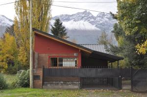 a small red house with mountains in the background at Los Pinos in El Bolsón