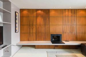 a living room with a fireplace and wooden cabinets at Comfortable Aircon Apartment Earls Court in London