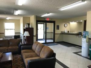 a living room with two couches and a kitchen at Clairmont Inn & Suites - Warren in Warren