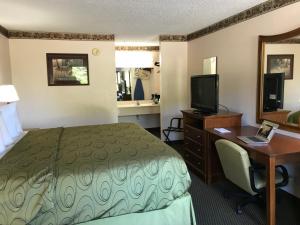 a hotel room with a bed and a desk with a computer at Clairmont Inn & Suites - Warren in Warren