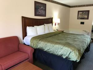 a hotel room with a bed and a couch at Clairmont Inn & Suites - Warren in Warren