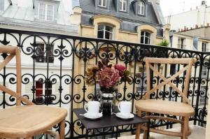 un balcone con 2 sedie e un tavolo con un vaso di fiori di Appartements Caumartin 64 a Parigi