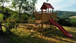 un parque infantil de madera con un tobogán en el césped en I Cuccioli, en Montescudaio