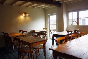 a restaurant with wooden tables and chairs and windows at B&B Hoeve de Steenoven in Damme +44 photos