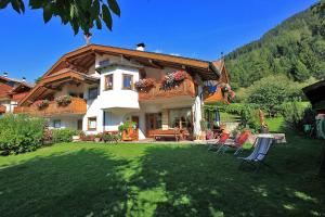 a house with two lawn chairs in front of it at B&B Ciasa Weber in Moena