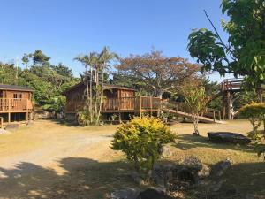 una casa en medio de un patio con árboles en Pension Yonaha Dake, en Kunigami