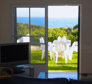 uma sala de estar com televisão e vista para o oceano em Casa Rosa Azul - Terracos de Benagil (Cliffside) em Benagil