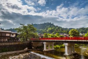 a red bridge over a river in a town at Honjin Hiranoya Annex in Takayama