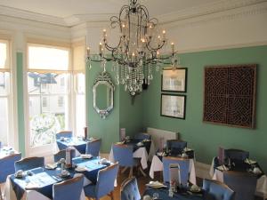 une salle à manger avec des tables bleues et un lustre dans l'établissement The Shirley, à Torquay