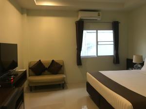 a bedroom with a bed and a chair and a window at Chiangrai Green Park Resort in Chiang Rai