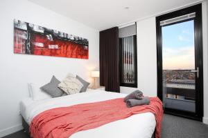 a bedroom with a bed with a red blanket and a window at StayCentral - Northcote Hill Penthouse in Melbourne
