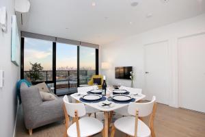StayCentral - Northcote Hill Penthouse في ملبورن: غرفة معيشة مع طاولة وكراسي بيضاء