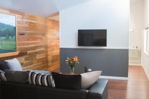 a living room with a couch and a tv on a wall at Mudgee Apartments on Horatio Street in Mudgee