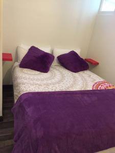 a bed with purple pillows in a room at Casa da Joana! in Murça