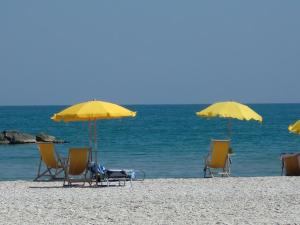 un gruppo di sedie e ombrelloni in spiaggia di Residence Marche - Residenza Ecologica a Lido di Fermo