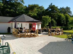 ein Restaurant mit Tischen und Sonnenschirmen in einem Park in der Unterkunft Gotland of Sweden - bed & breakfast in Tingstäde