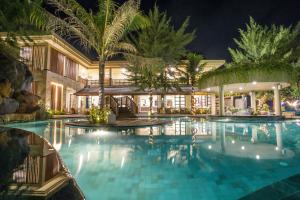 a swimming pool in a resort at night at Vila Ombak in Gili Trawangan