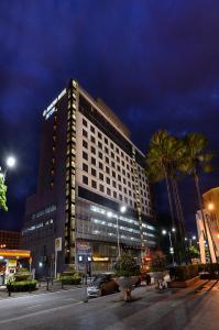 un grande edificio di notte con palme di fronte di Horizon Hotel a Kota Kinabalu