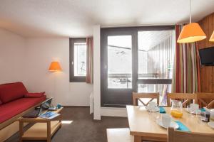 - un salon avec un canapé rouge et une salle à manger dans l'établissement Résidence Pierre & Vacances Les Combes, aux Menuires
