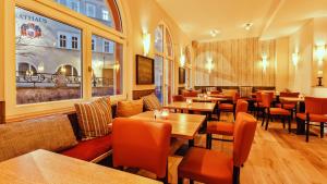 ein Restaurant mit Holztischen und orangefarbenen Stühlen in der Unterkunft Hotel Thüringer Hof in Sondershausen