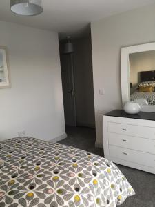 a bedroom with a bed and a dresser and a mirror at The Hatherans in Portstewart