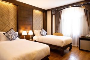 een hotelkamer met 2 bedden en een raam bij Elliebum Boutique Hotel in Chiang Mai