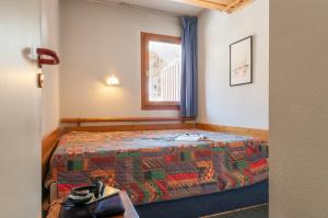 a bedroom with a bed with a quilt on it at Résidence Pierre & Vacances Le Peillon in Méribel